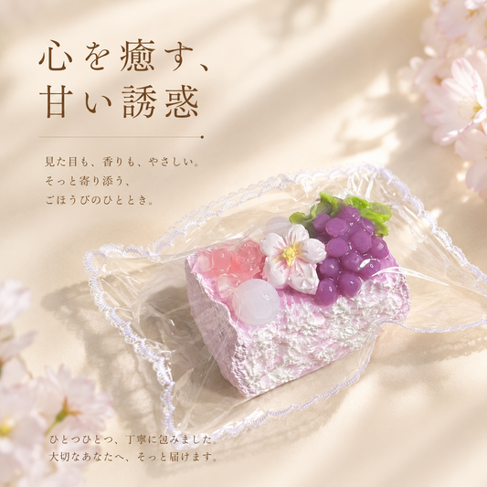 Pink cake squishy toy in a candy-style lace-trimmed clear pouch, cherry blossom branches blurred in the background