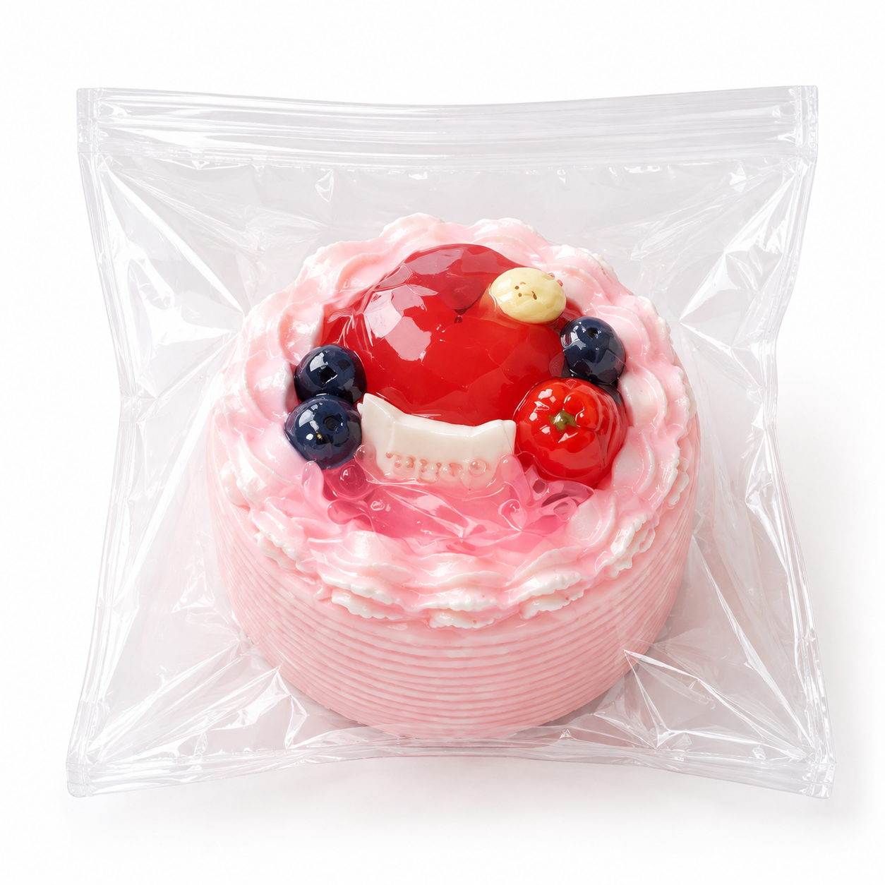 Pink mini cake squishy featuring a glossy red apple and blueberry toppings sealed in clear packaging.