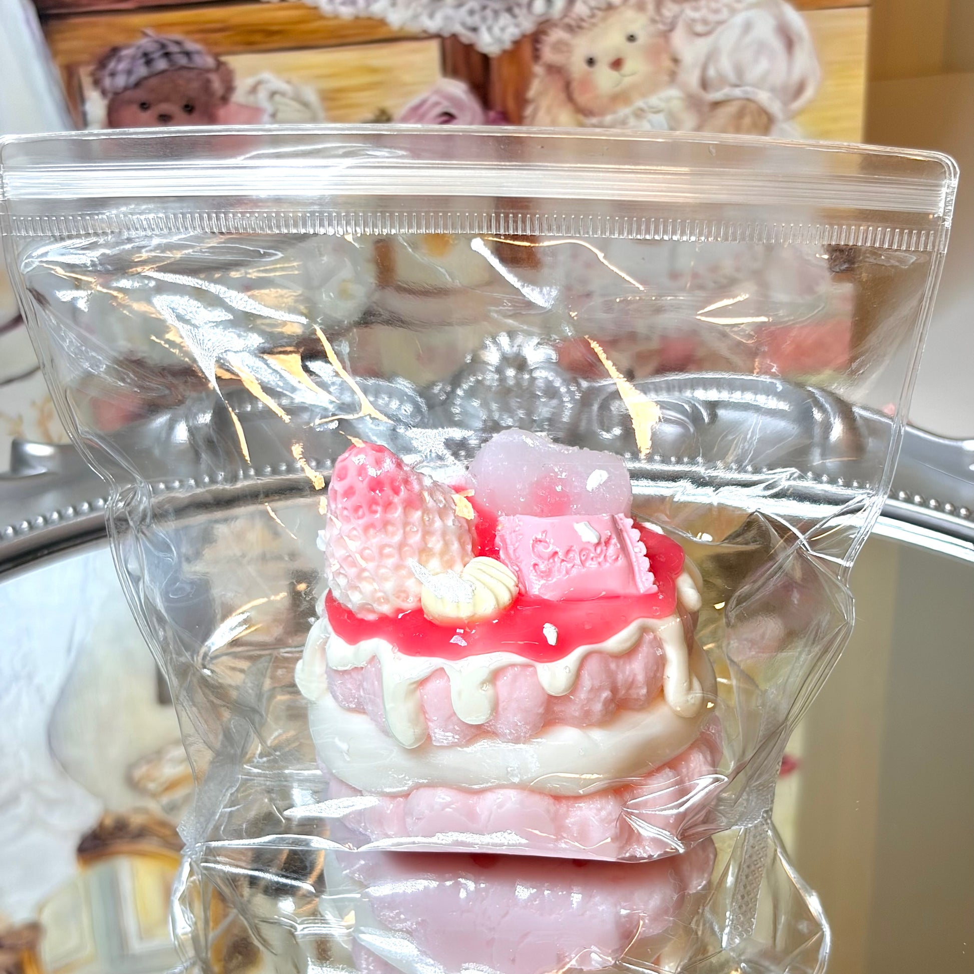 Round strawberry cake squishy toy inside a clear plastic bag resting on a silver tray.