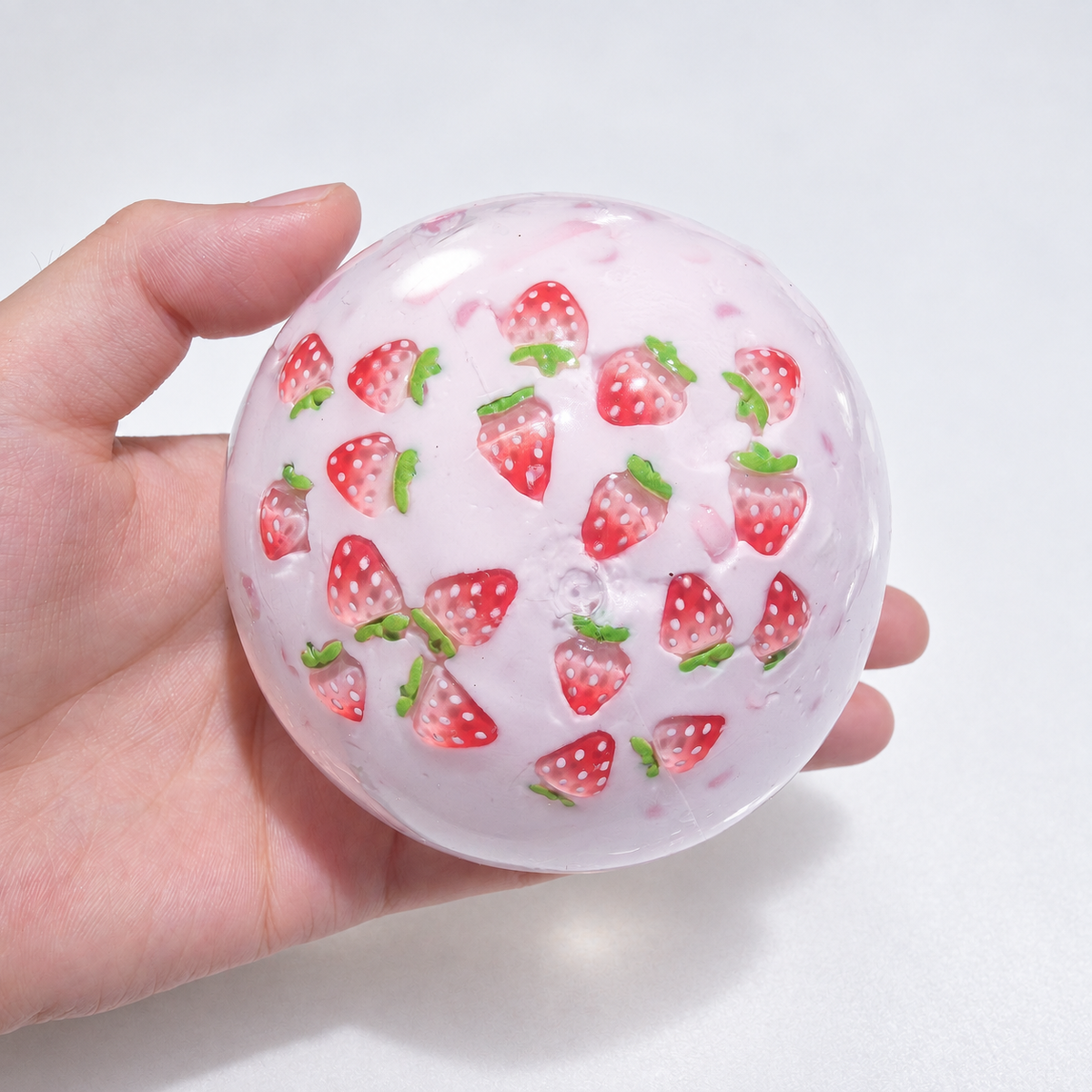 Translucent pink sensory squishy ball with visible resin strawberry-shaped pieces; Strawberry Milkshake handmade sensory squishy ball, product photo 4