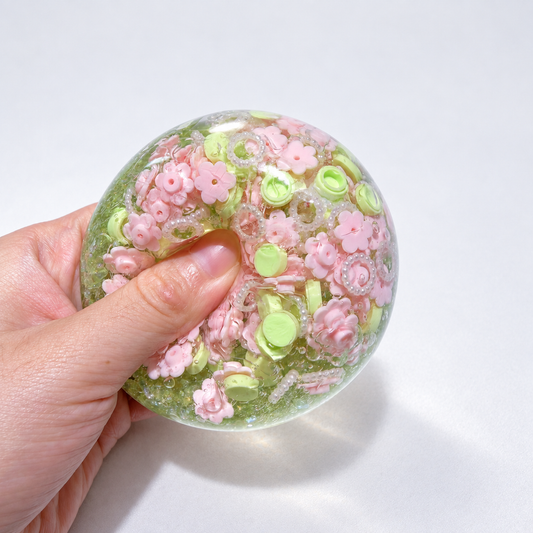 Green-tinted sensory squishy ball with resin pink flower-shaped pieces and small decorative beads; Spring Blossom handmade sensory squishy ball, product photo 2
