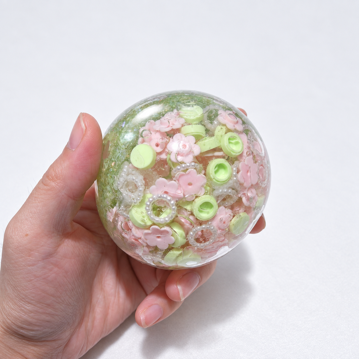 Green-tinted sensory squishy ball with resin pink flower-shaped pieces and small decorative beads; Spring Blossom handmade sensory squishy ball, product photo 3