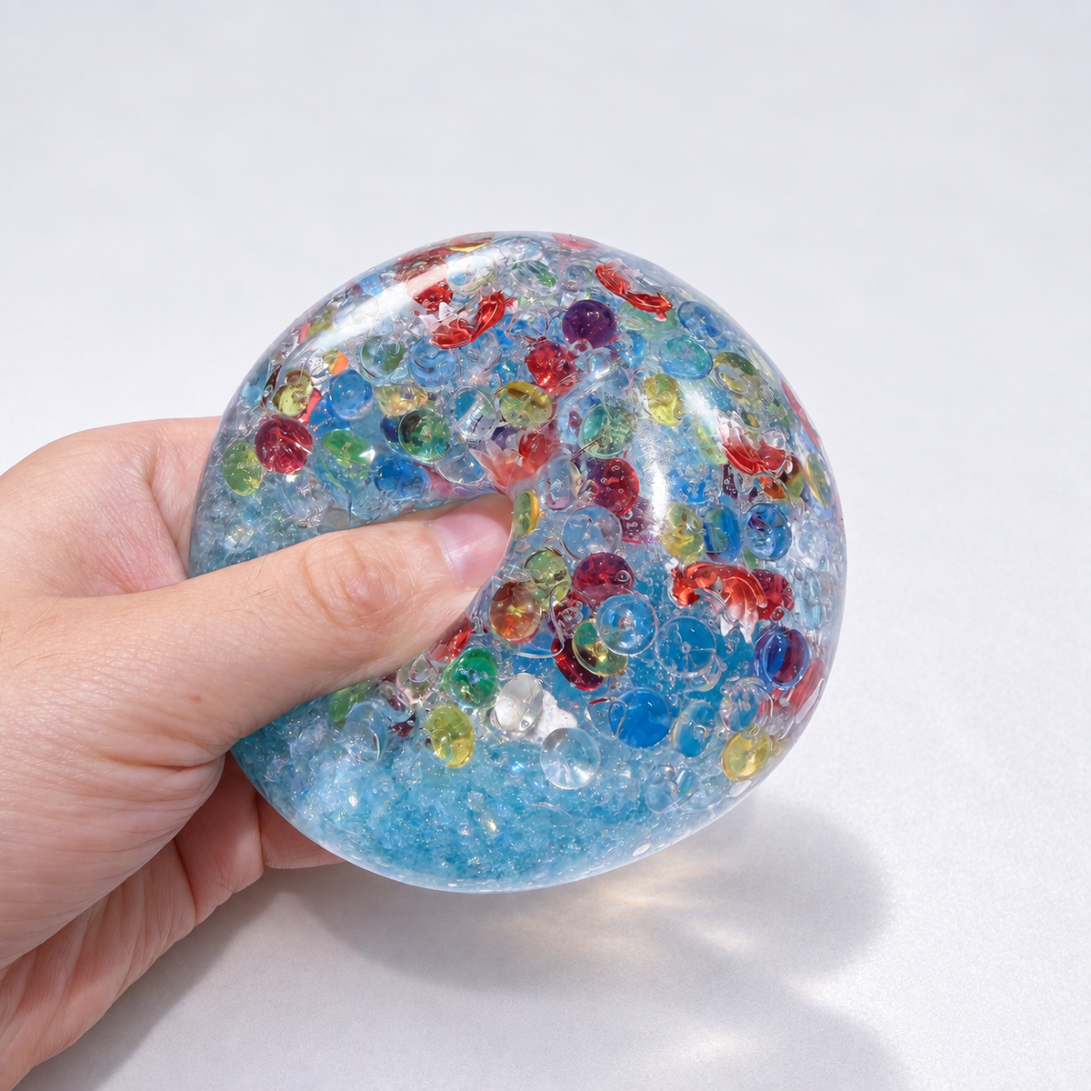 Blue translucent sensory squishy ball with colorful resin fish-shaped details; Floating Light Fish handmade sensory squishy ball, product photo 1