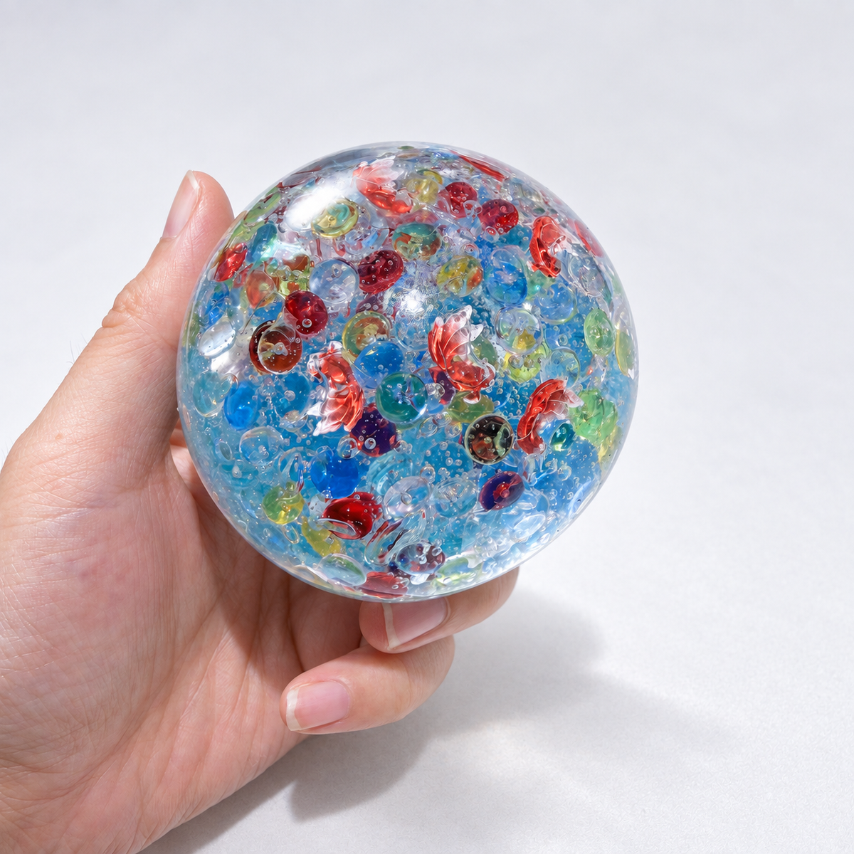 Blue translucent sensory squishy ball with colorful resin fish-shaped details; Floating Light Fish handmade sensory squishy ball, product photo 2