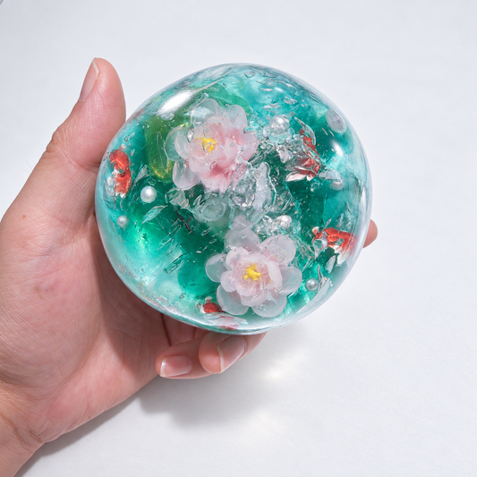 Teal sensory squishy ball with resin lotus-inspired flowers and small koi-shaped details; Koi Plays Among Lotus handmade sensory squishy ball, product photo 1