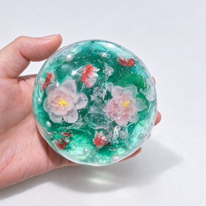 Teal sensory squishy ball with resin lotus-inspired flowers and small koi-shaped details; Koi Plays Among Lotus handmade sensory squishy ball, product photo 4