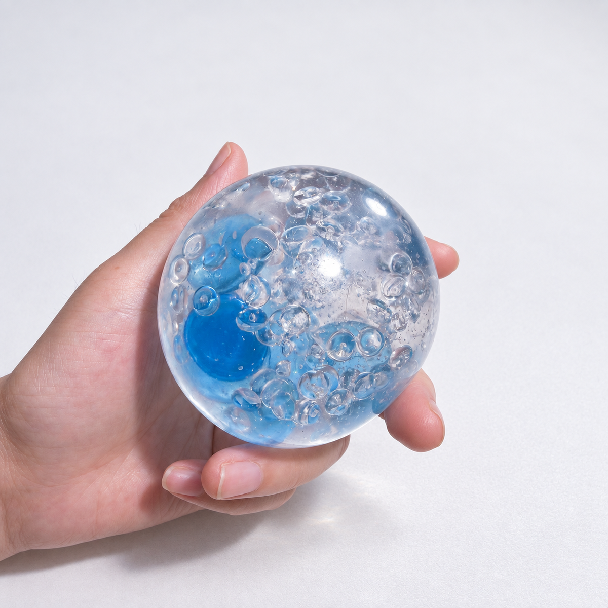 Clear pale-blue sensory squishy ball with blue and transparent resin bead details; Azure Water World handmade sensory squishy ball, product photo 1