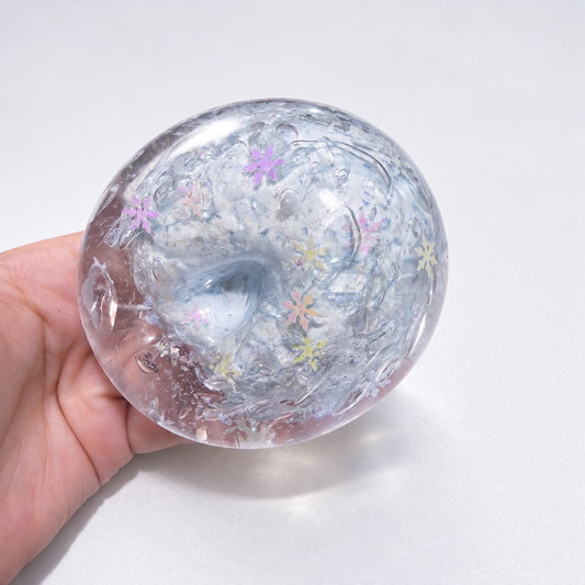 Pale translucent snowflake-themed ball with colorful details held in a hand