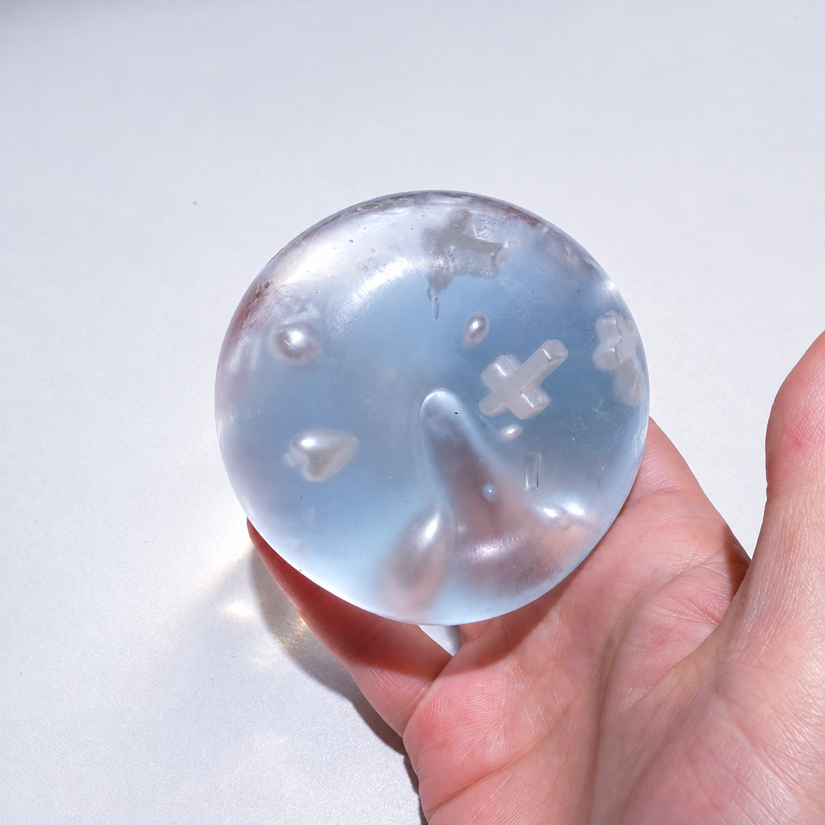Blue sensory ball held from another side, with cross and pearl decorations