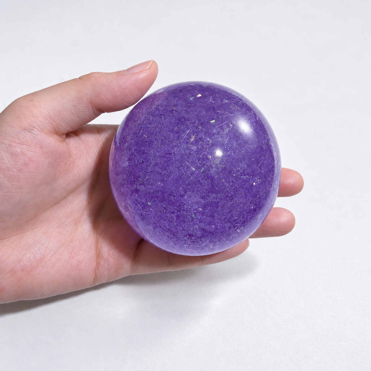 Purple translucent squishy ball with a crystal-inspired look held in a hand